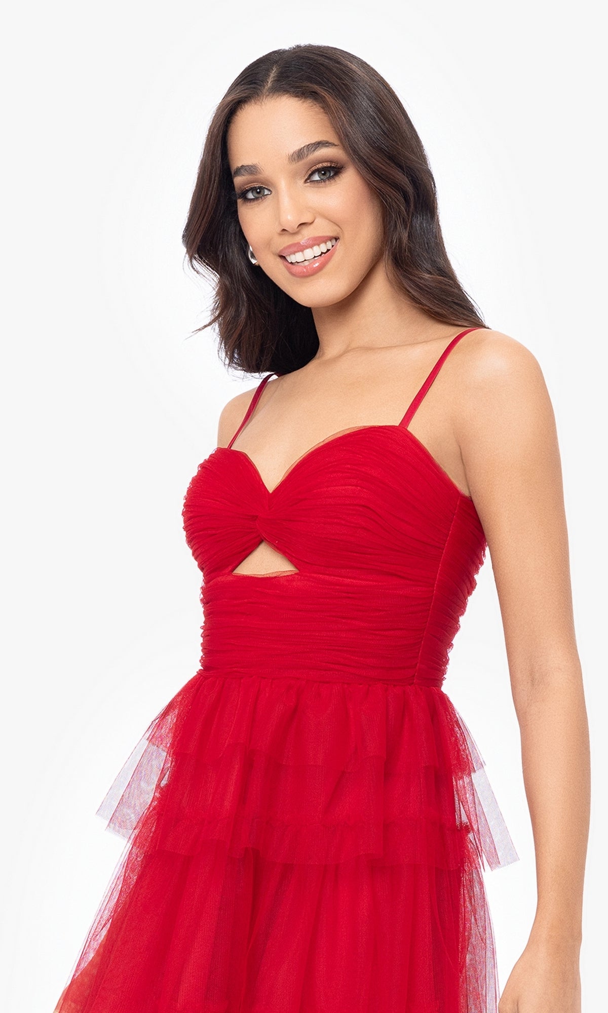 Woman smiling at the camera in the Cut-Out Short Ruffled Homecoming Dress 5098BN, featuring a sleeveless red tulle A-line design with thin straps, a ruched sweetheart bodice, and a small cutout under the bust.